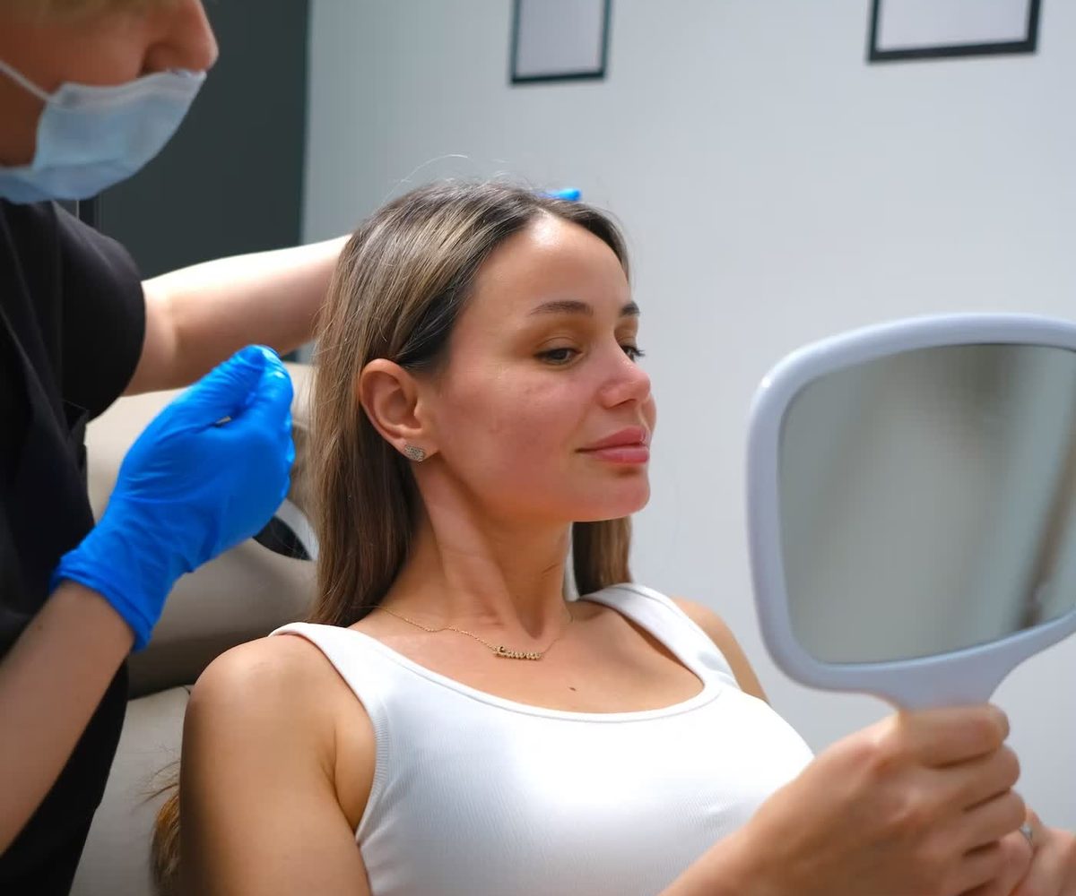 A client looking at her result in a hand mirror after treatment.